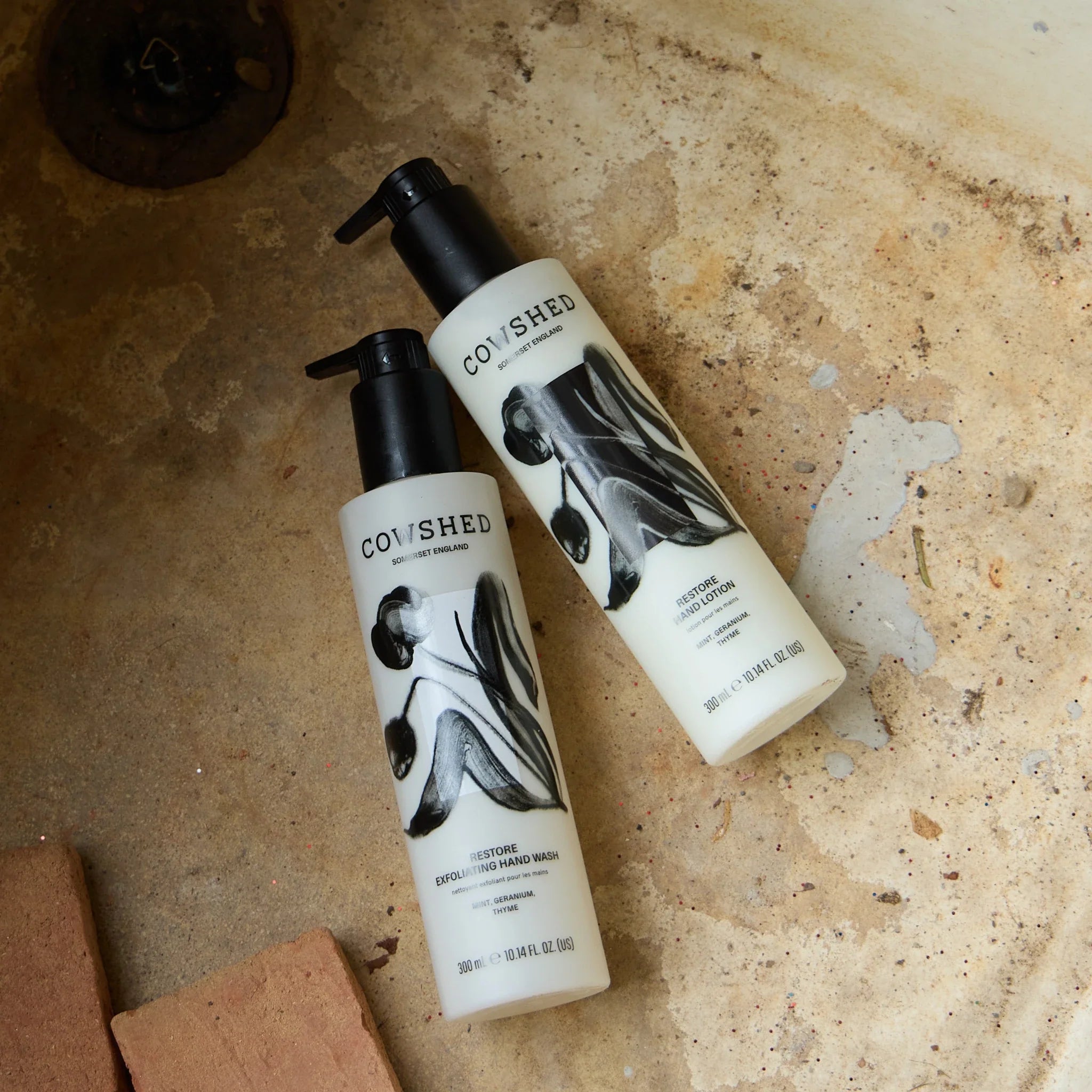 Two Cowshed Restore hand care bottles in a sink