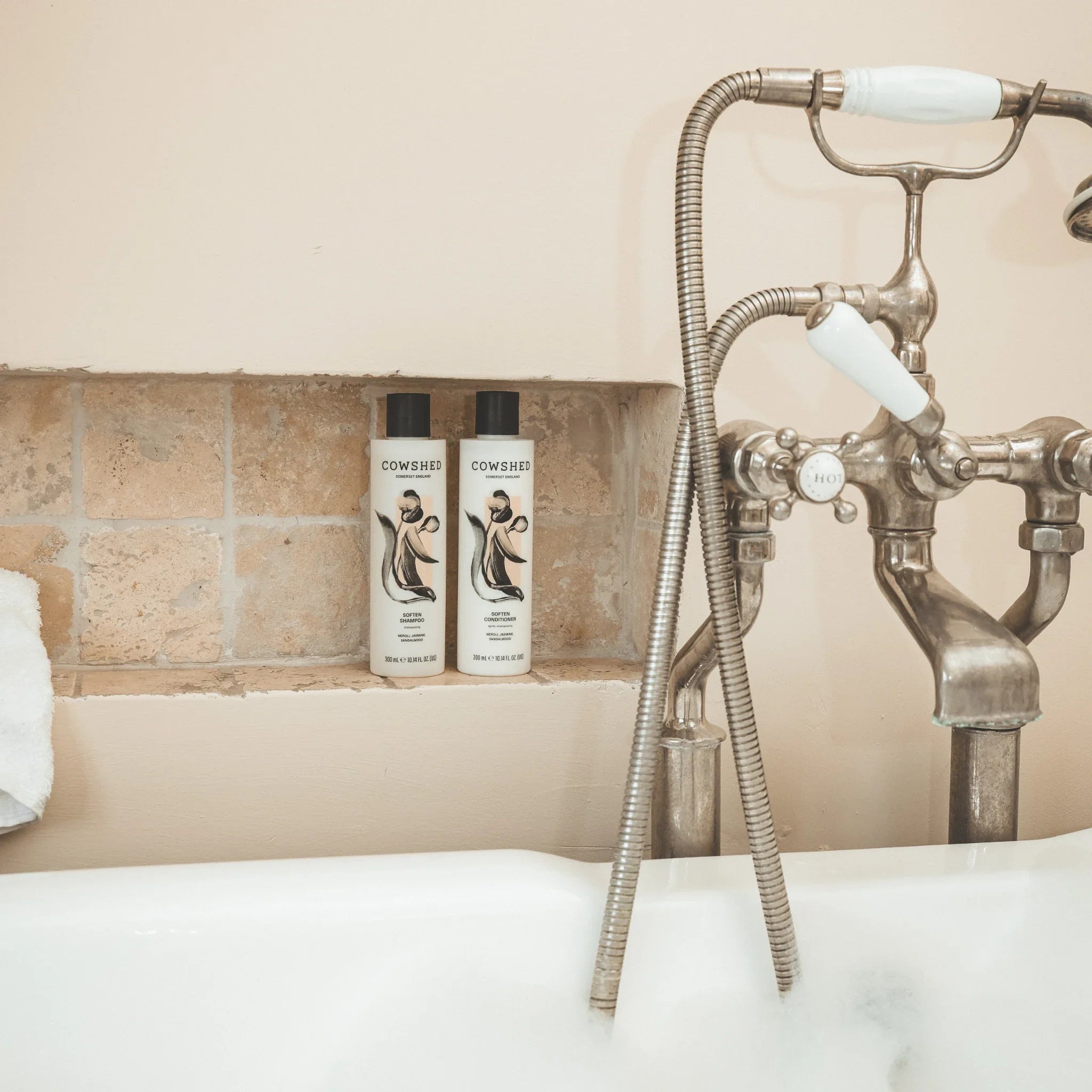 Cowshed Soften Shampoo & Conditioner on a bathroom shelf with a vintage-style shower head