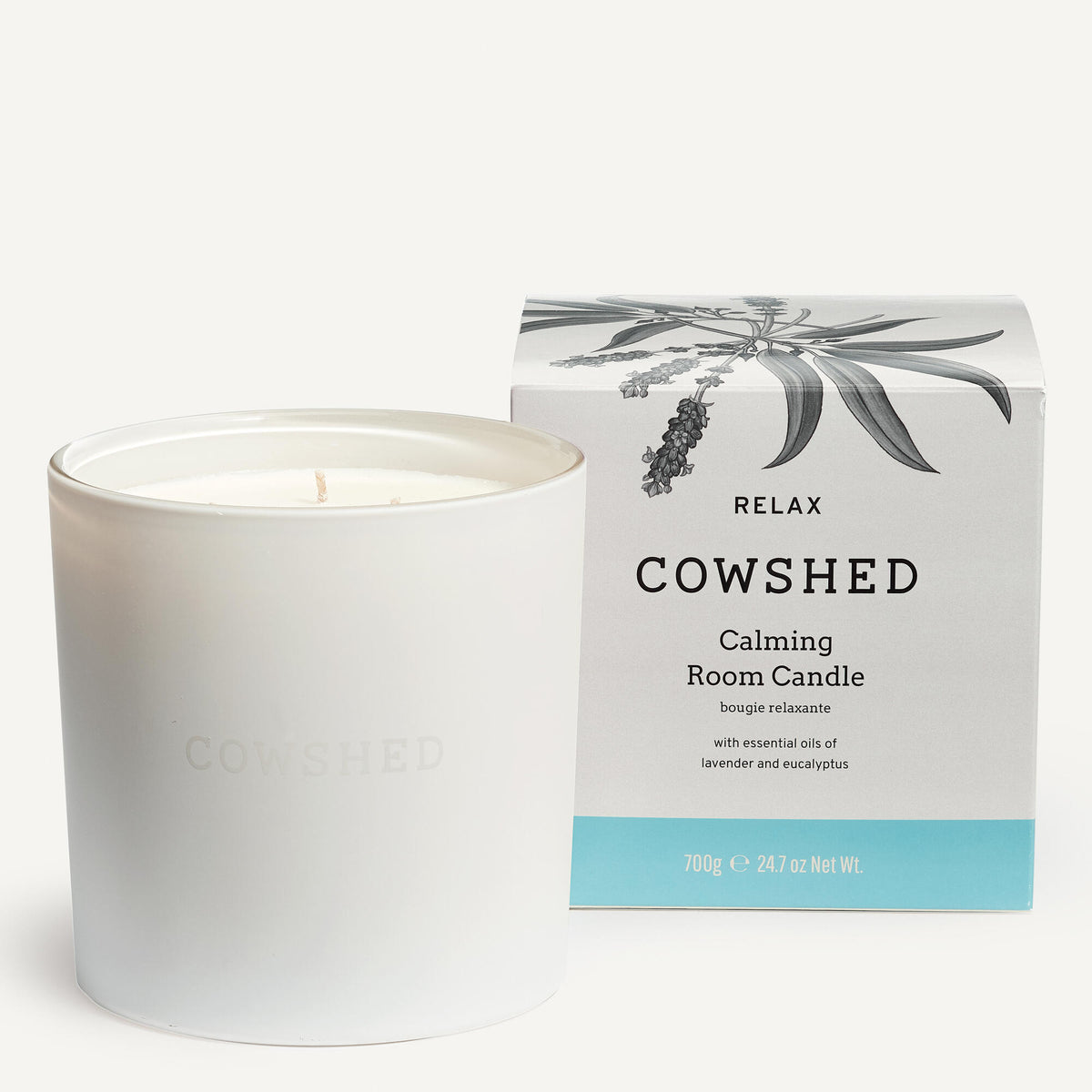 A white candle with a label that reads 'COWSHED Relax Calming Room Candle' in a box, featuring a graphic of a plant.