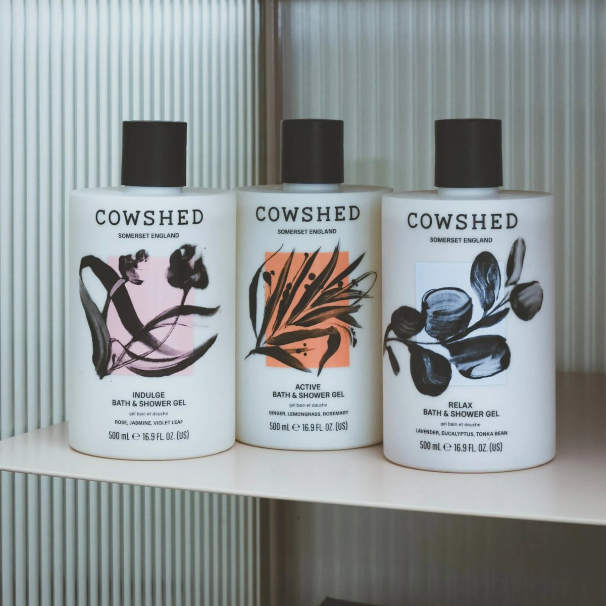 Three Cowshed bath and shower gel bottles on a shelf with a neutral background