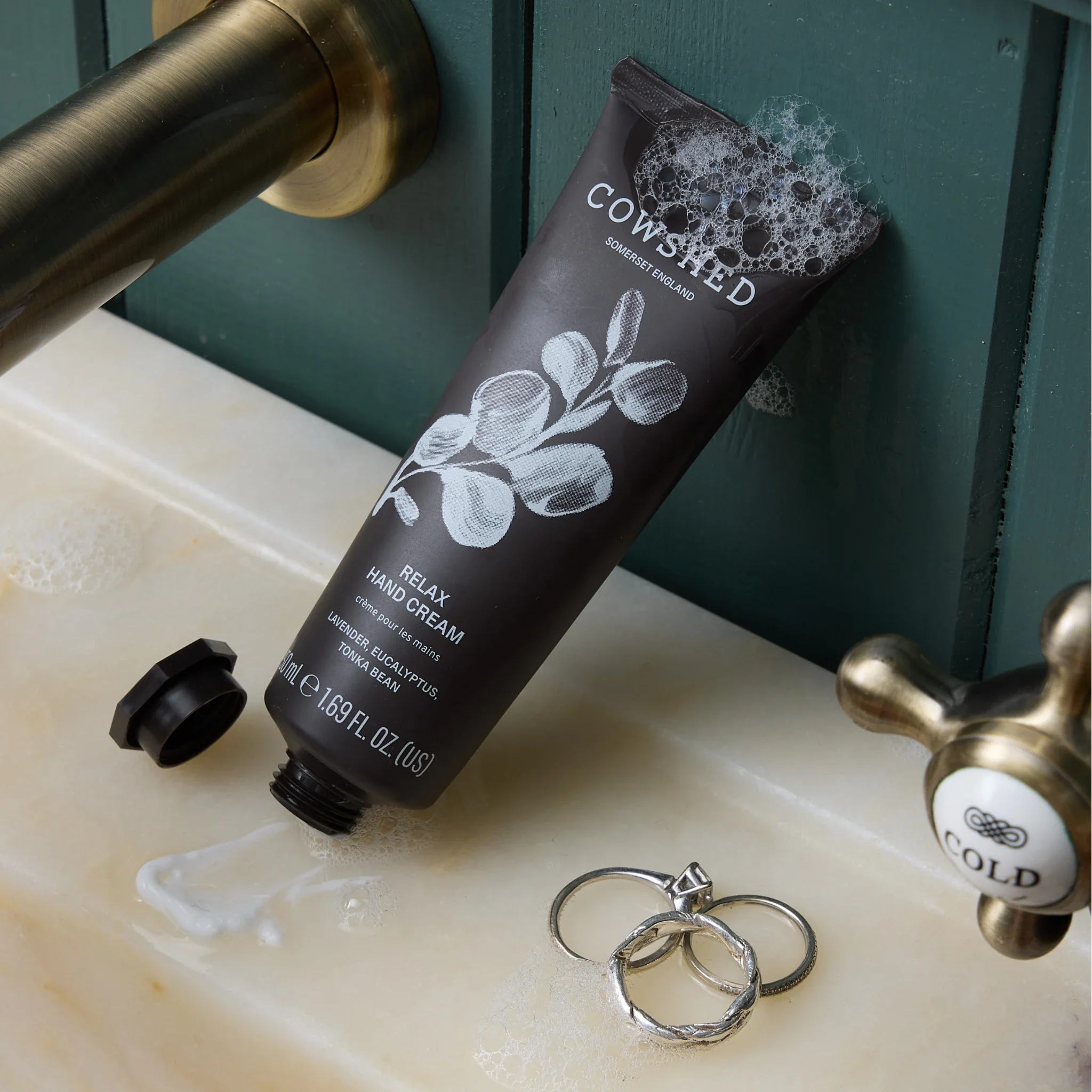 Cowshed hand cream on a sink with rings and soap bubbles