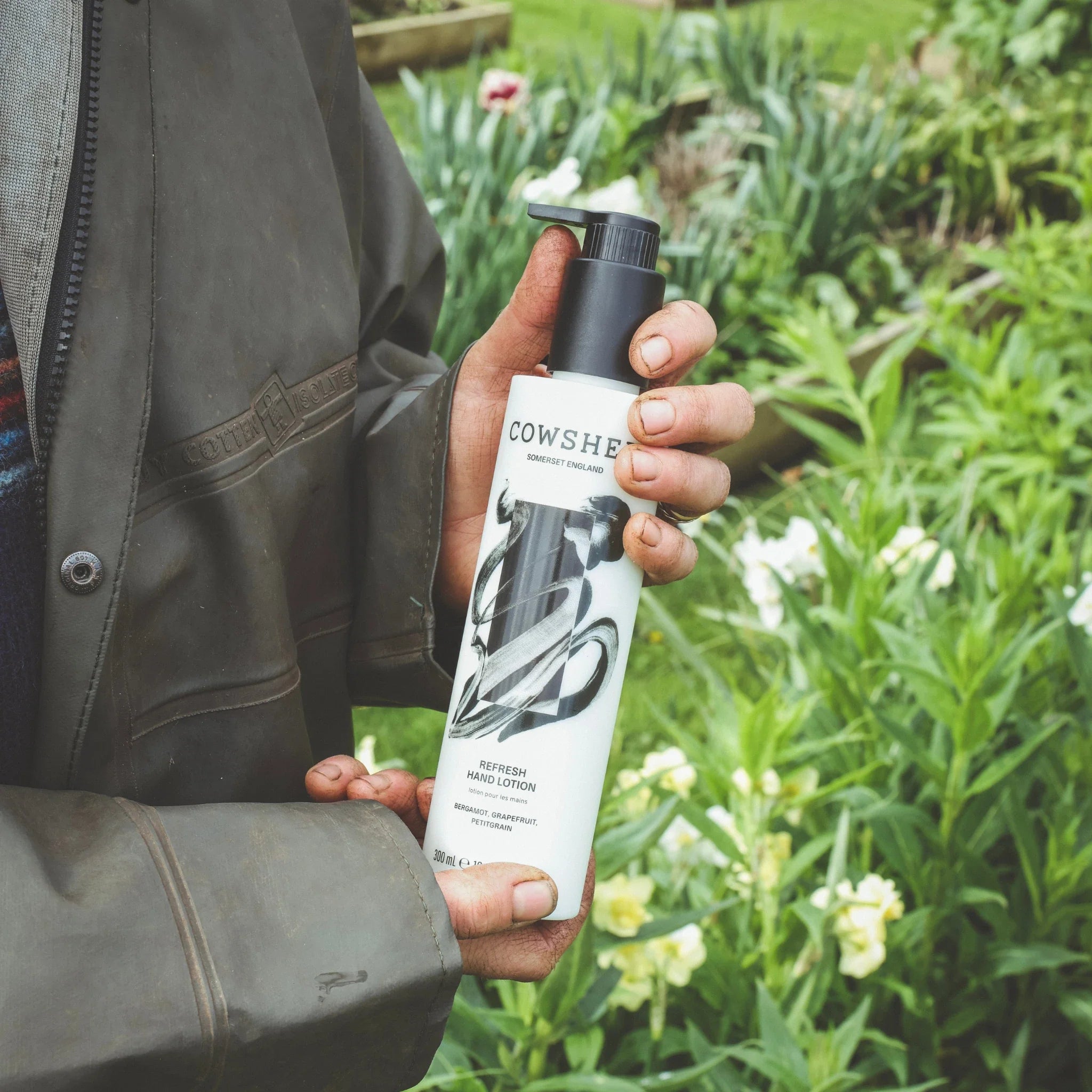 Hands holding the refresh hand lotion 300ml in a garden