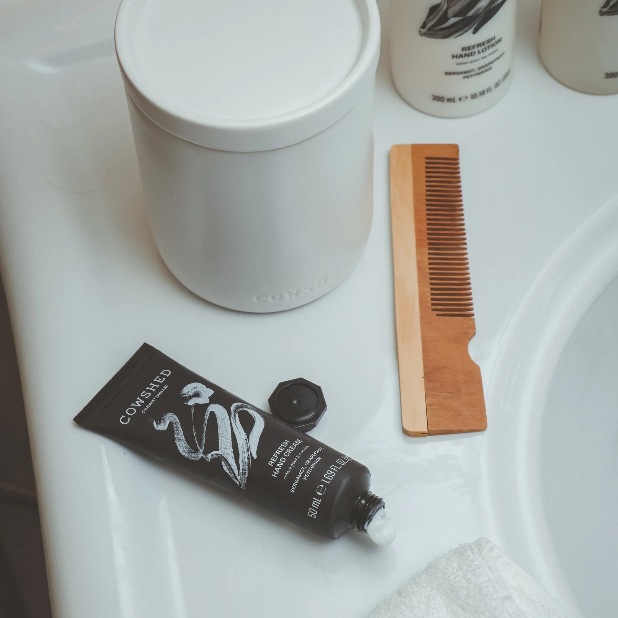 Cowshed Refresh hand cream on a bathroom sink with a combe