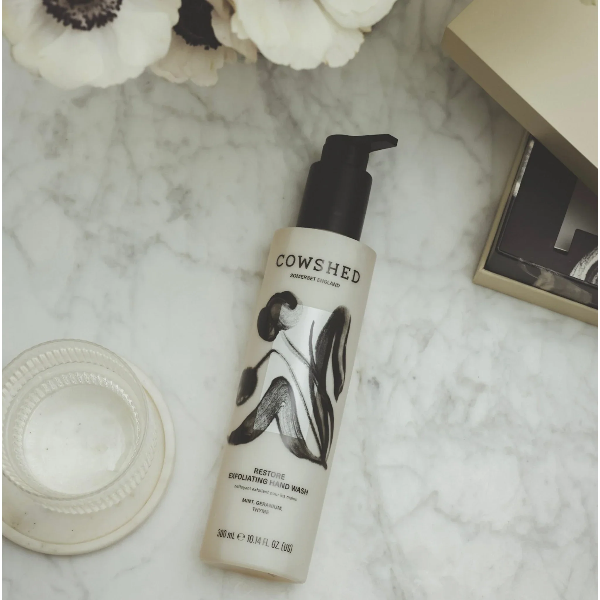 Cowshed hand wash bottle on a marble surface with decorative elements