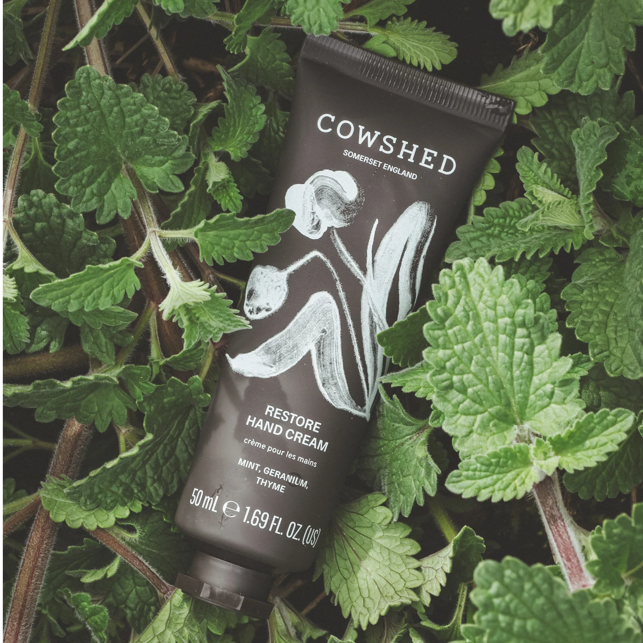 Cowshed Restore Hand Cream tube surrounded by mint leaves