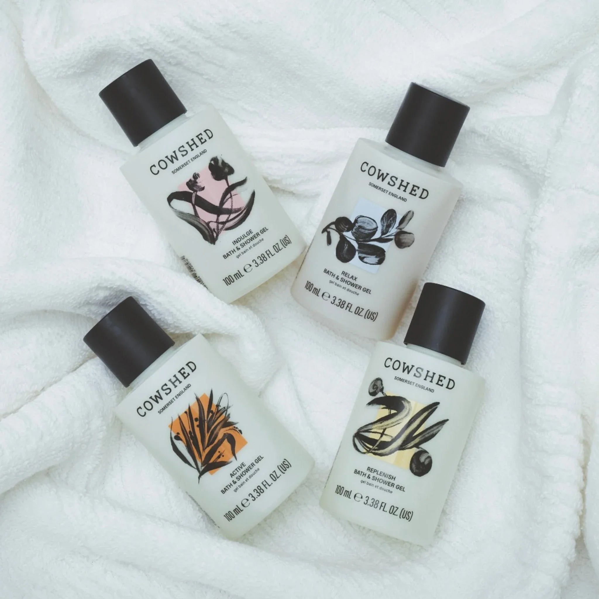 Four Cowshed shower gels on a white towel