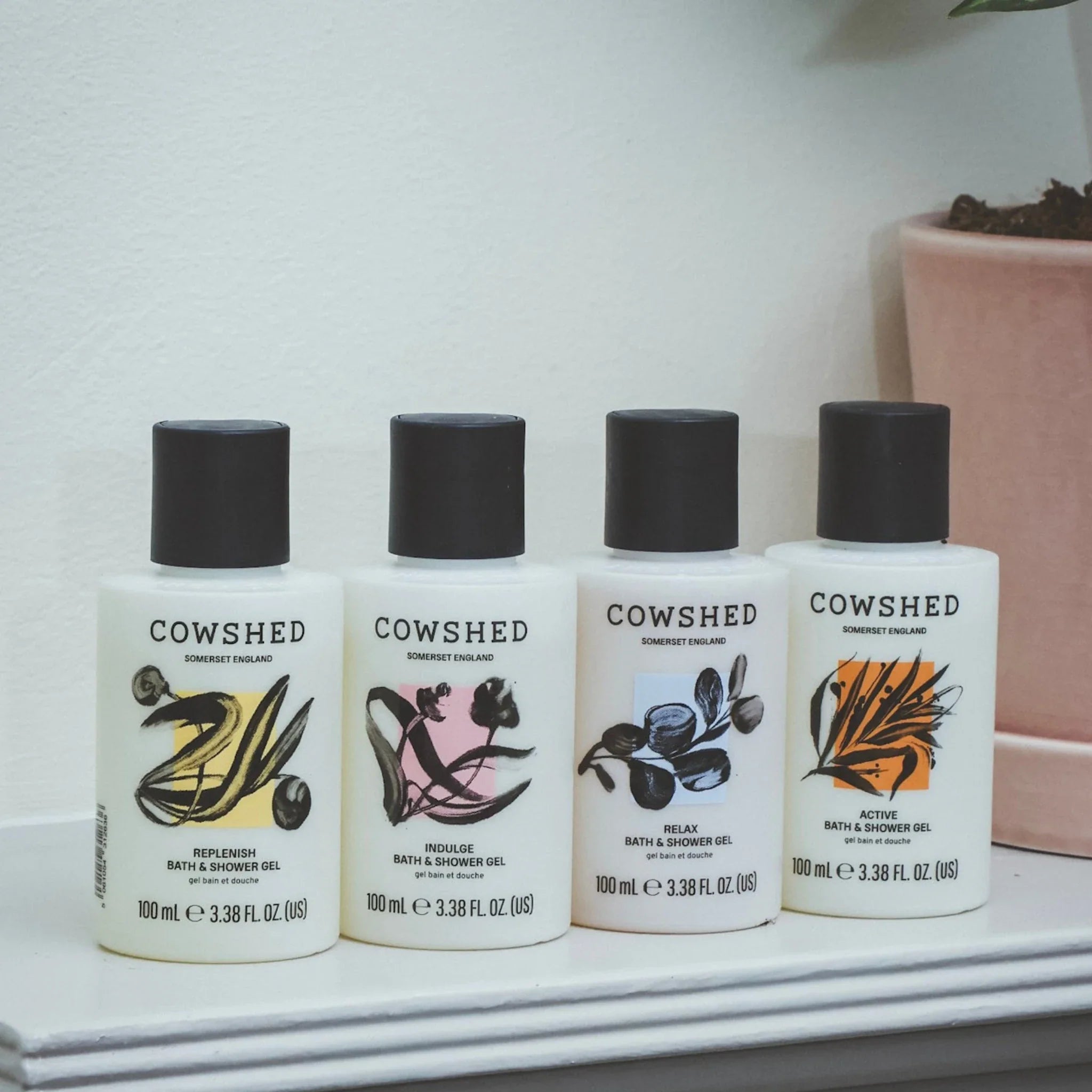Four Cowshed bath and shower gel bottles on a shelf with a neutral background.