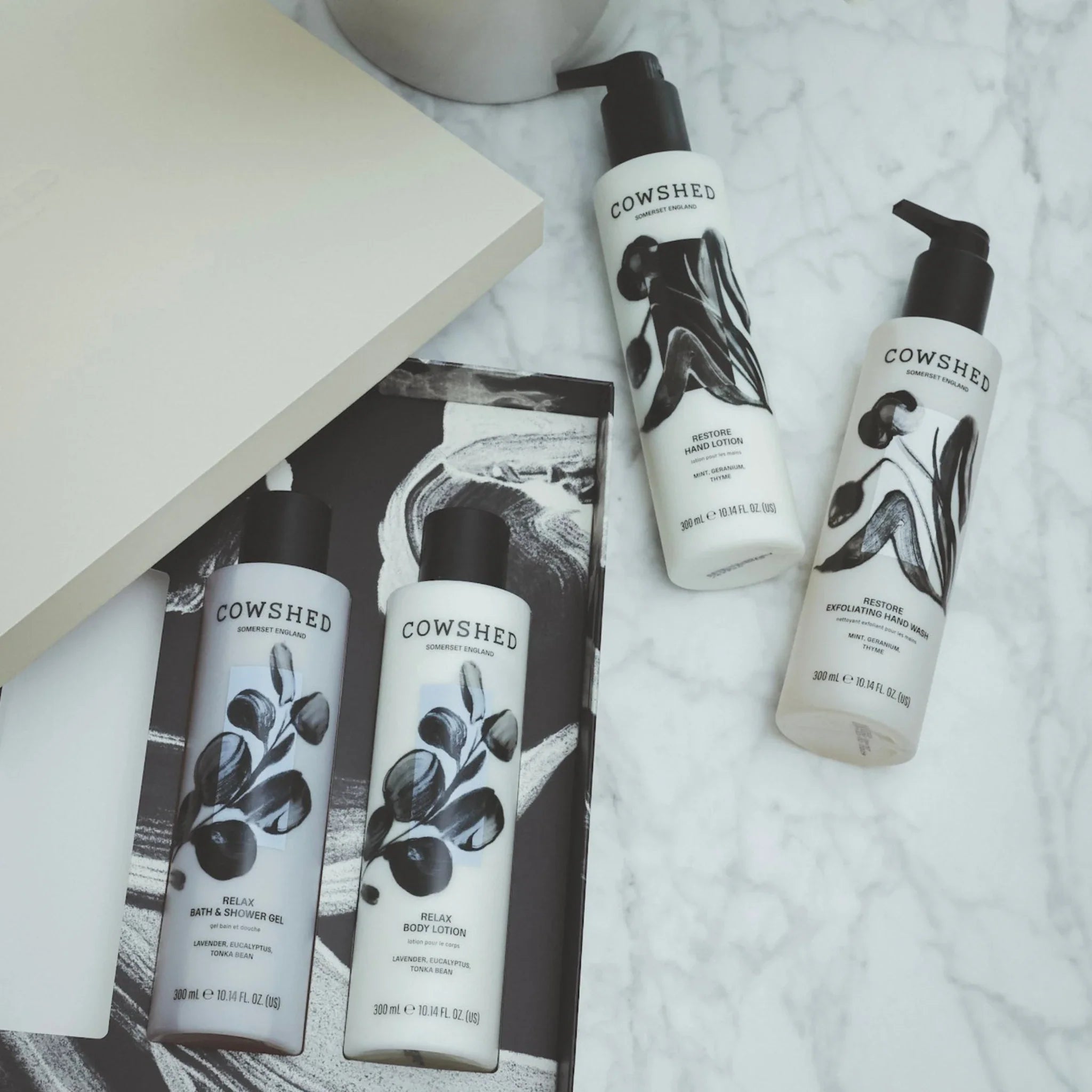 Cowshed body care products on a marble surface with a magazine.