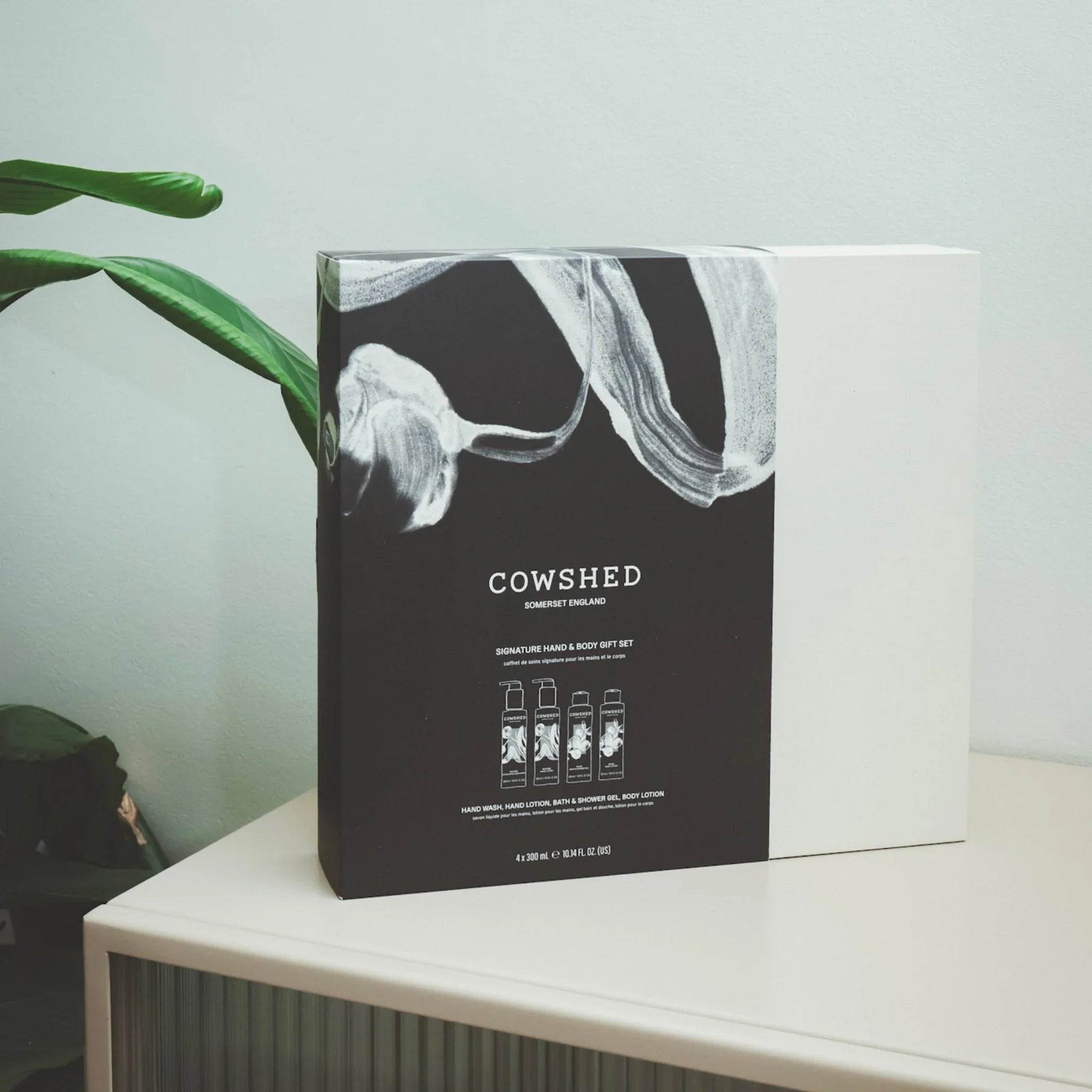 Cowshed product packaging on a white surface with a plant in the background