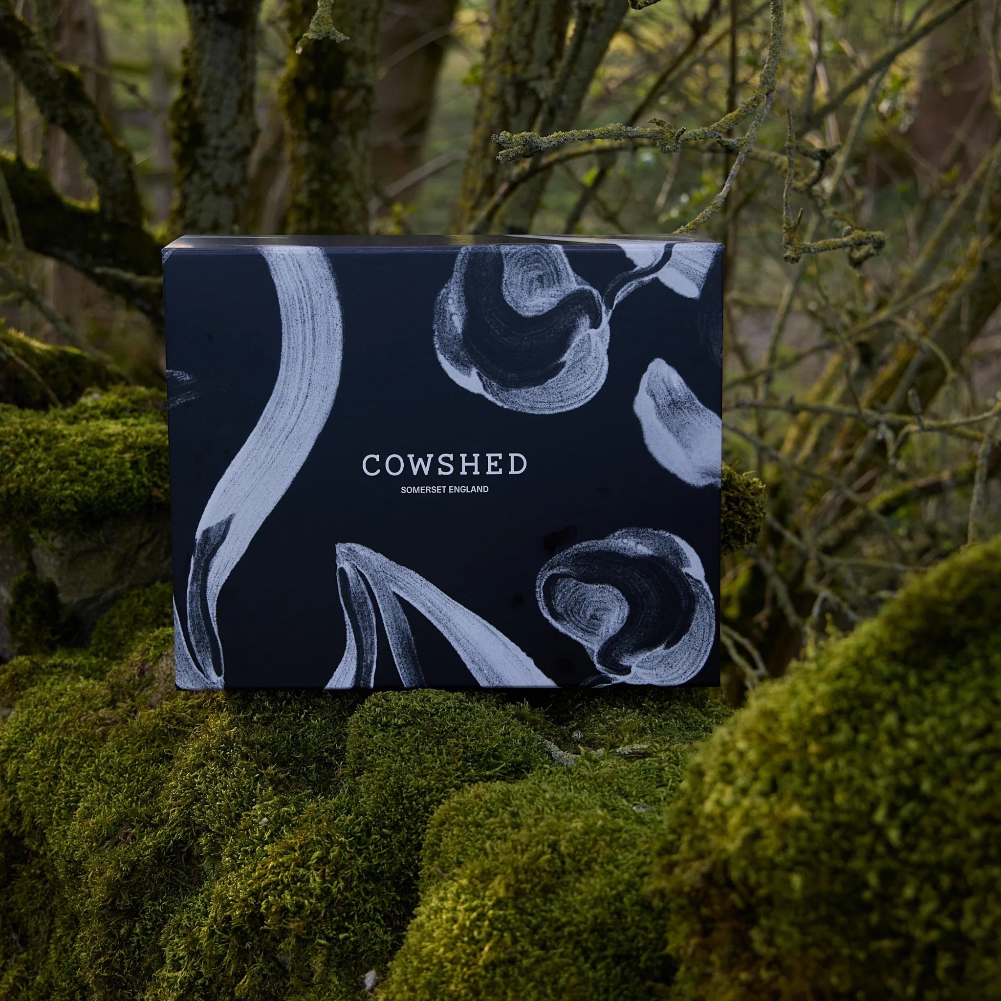 Cowshed product packaging with floral design on a natural background