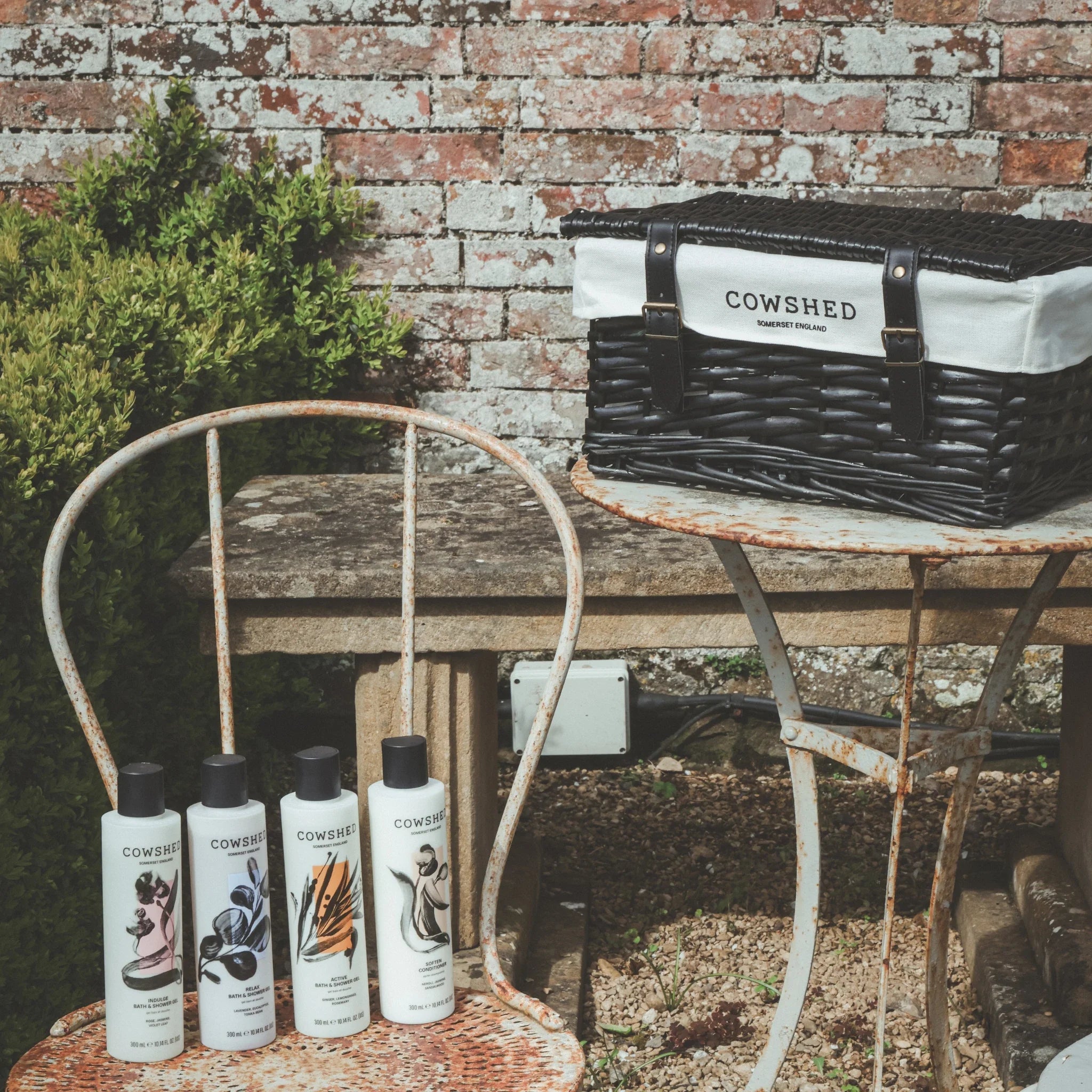 Cowshed products on a rustic table outdoors with a brick wall background