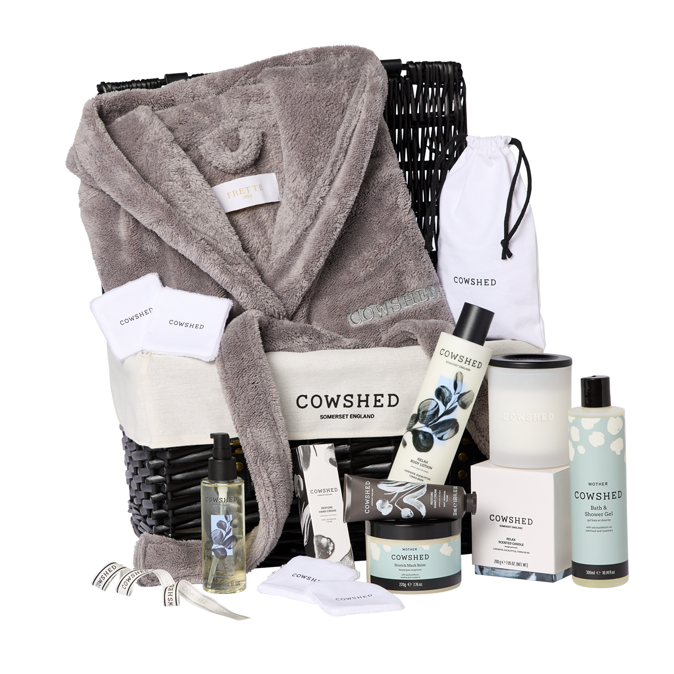 Cowshed gift basket with robe, candles, and skincare products on a white background