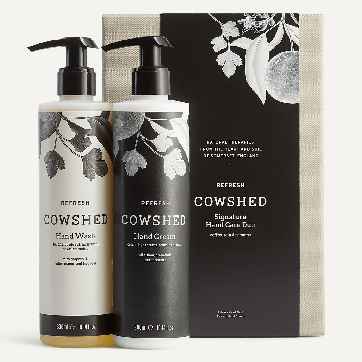 A hand care duo set by Cowshed, including a bottle of hand wash and hand cream, both with pump dispensers, and a black and white designed box.
