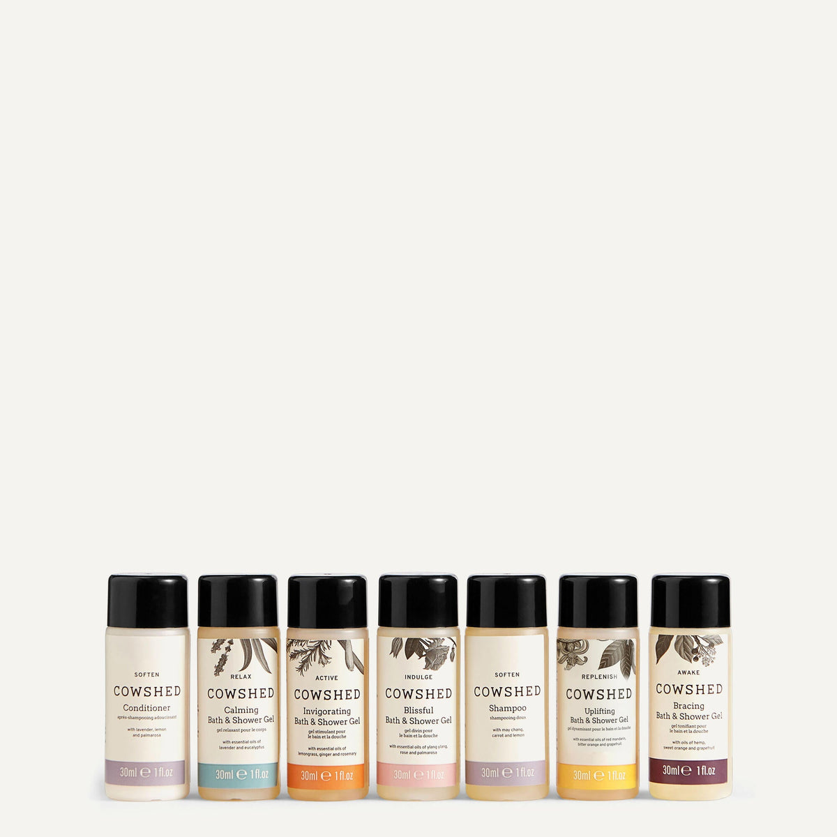 A set of eight miniature bottles of Cowshed shower gel, arranged in a row on a white background.