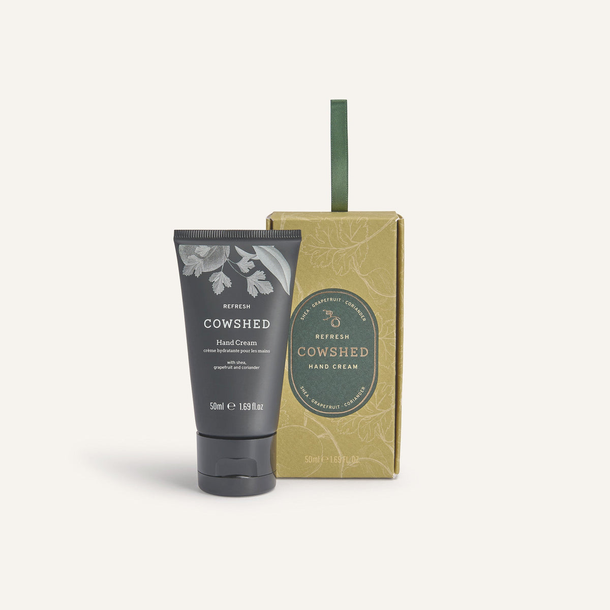 A tube of Cowshed hand cream next to its packaging box, with a Christmas-themed design.