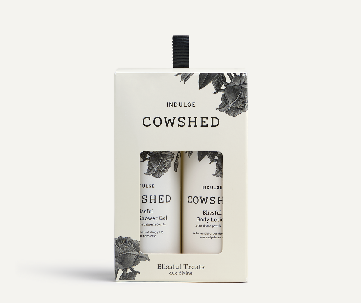 Indulge Cowshed 'Blissful Treats' duo box set containing Indulge Cowshed Blissful Shower Gel and Blissful Body Lotion, in a cream-colored box with black text and botanical illustrations.